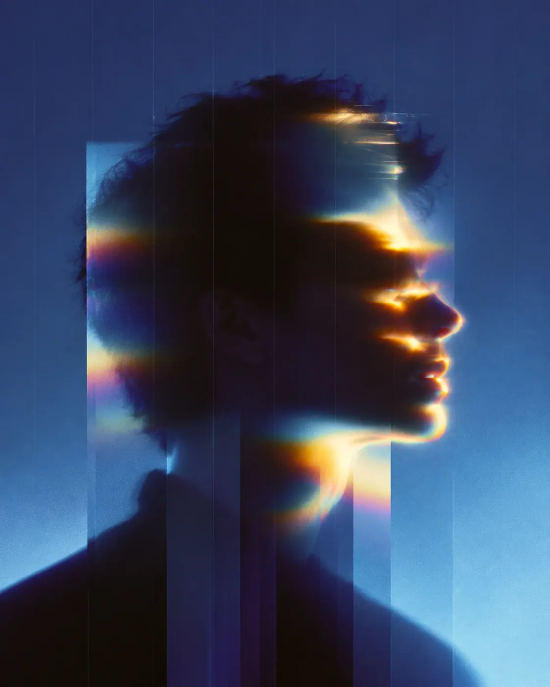 Silhouetted profile of a man lit by blue and gold light through vertical glass strips