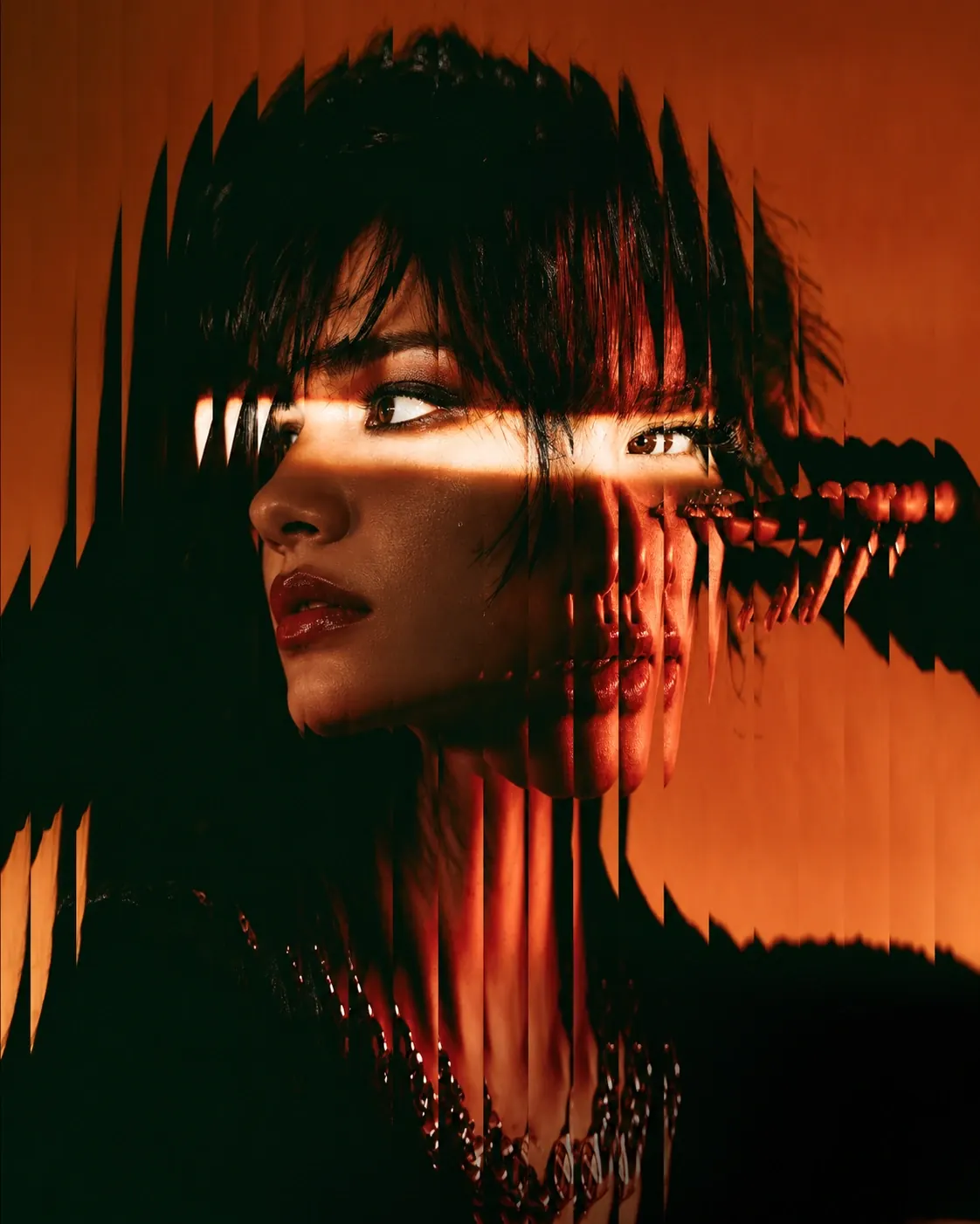 Woman in orange light, her face split by a reeded-glass distortion effect